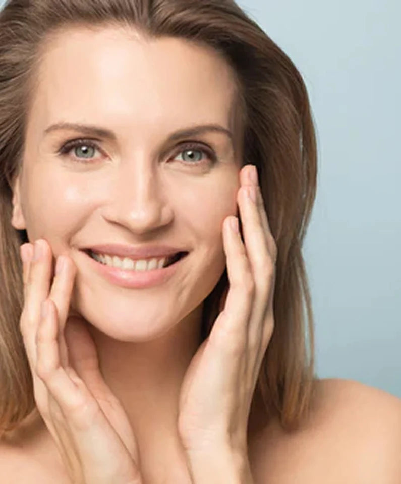 Woman with clear, even skin touching her face.